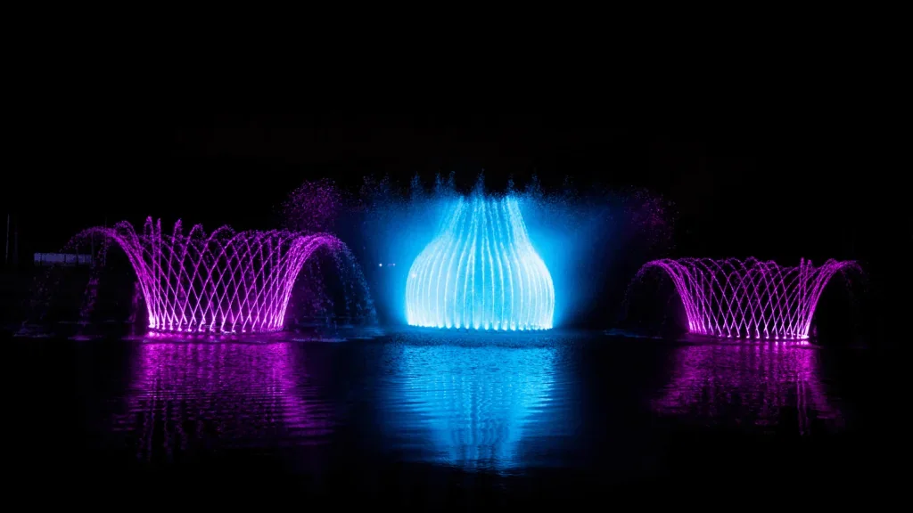 Fontes iluminadas em azul e roxo durante espetáculo noturno