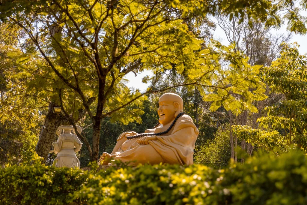 Estátua entre árvores no Templo Budista de Foz